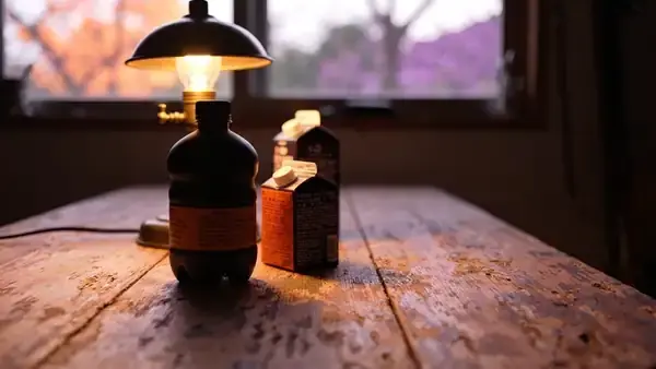 Brass table lamp switched off at dusk beside an empty small bottle and a closed carton